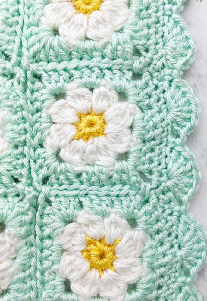 Repare na delicadeza desse tapete de crochê com square colorido formando margaridas brancas no fundo verde!