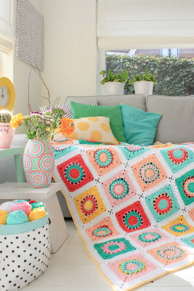 Tapete de crochê com square colorido combinando perfeitamente com a decoração colorida e alegre da sala de estar.