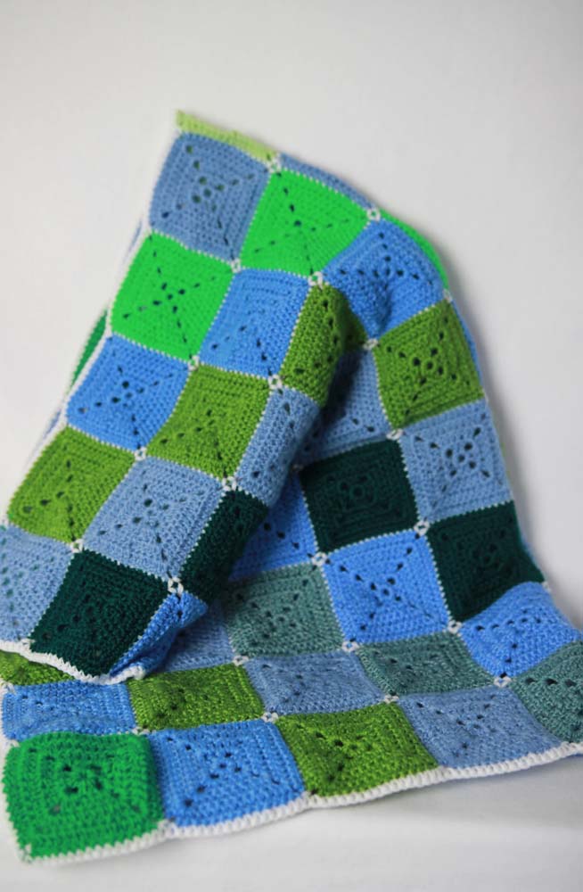 Uma diagonal de cada cor neste tapete de crochê com square colorido azul, verde e cinza.