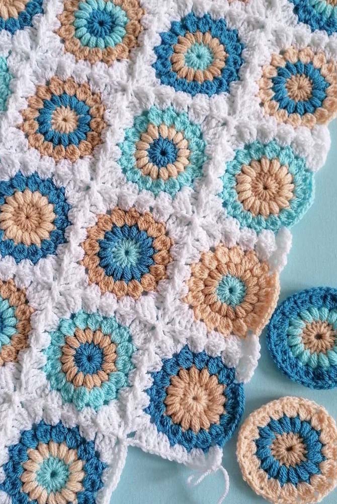 Fofo e delicado, um tapete de crochê com square colorido composto de flores com três camadas redondas e coloridas no fundo branco.