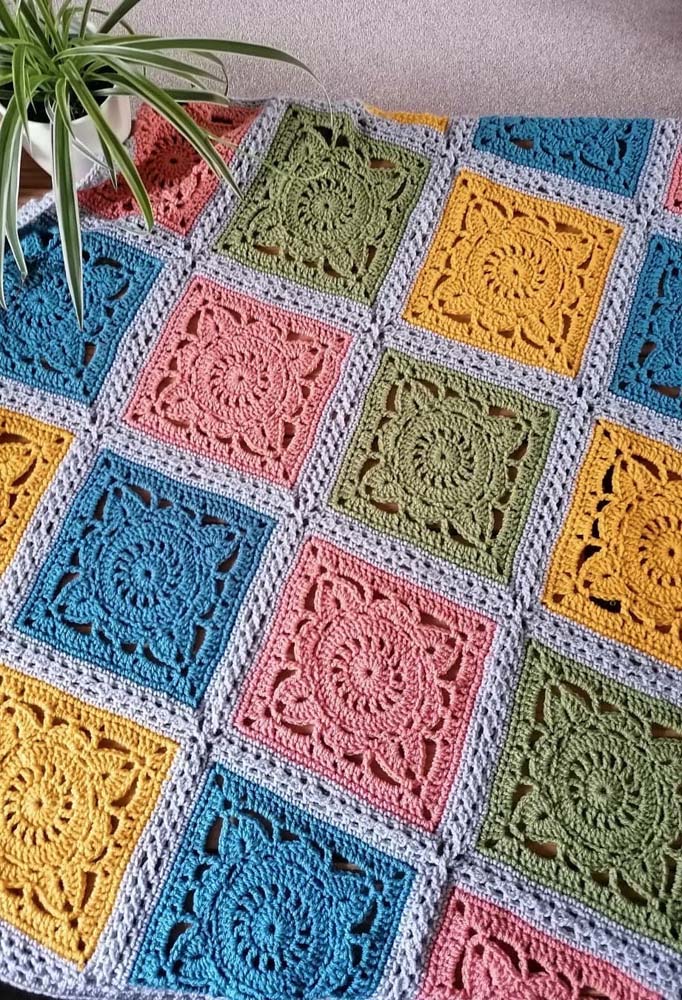 Tapete de crochê com square quadrado formando diagonais de cor.