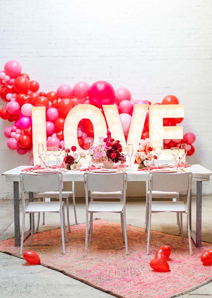 Um letreiro luminoso com a palavra love destaca a mesa de jantar nessa outra ideia de decoração de bodas de namoro