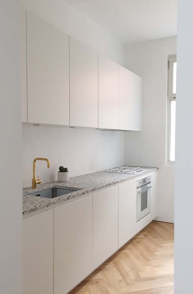 Já essa cozinha planejada pequena com bancada de granito apostou no branco para garantir a sensação de amplitude