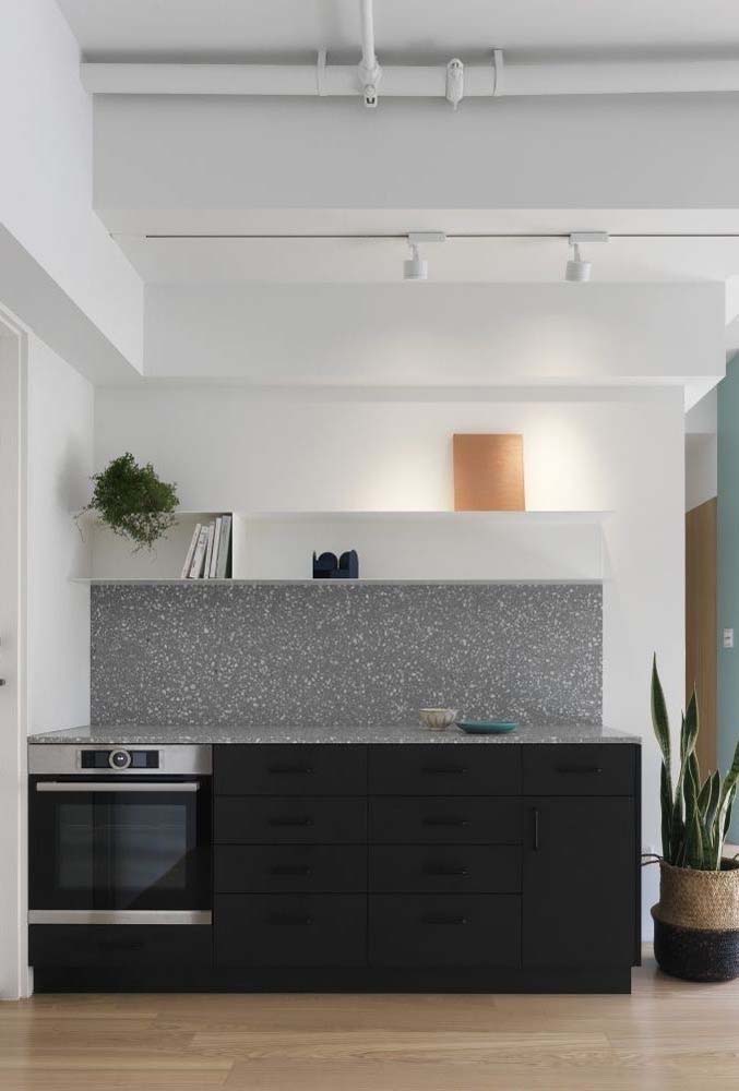 O granito cinza ficou perfeito na cozinha de armários pretos e fundo branco