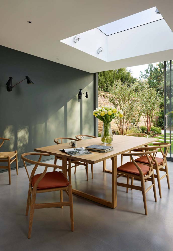 A parede verde musgo na parede combina perfeitamente com mesa e cadeiras de madeira, com estofado terracota. 