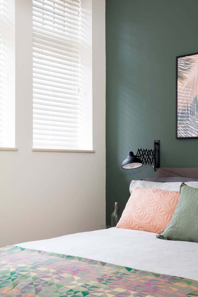 Para manter o ambiente bem iluminado, só a parede de cabeceira da cama ganha uma camada de verde musgo escuro. 
