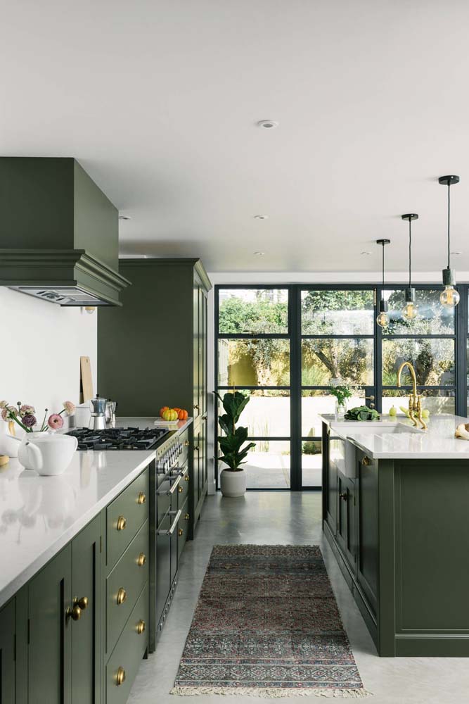 Cozinha branca ampla e elegante com todos os armários verde musgo e metais dourados.