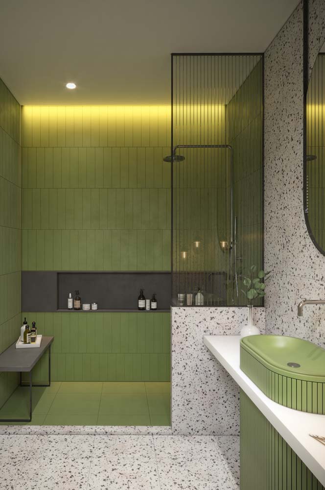 Azulejo metro verde musgo no box e granilite branco e cinza no restante do banheiro: combinação que une tendências de cores e revestimentos. 
