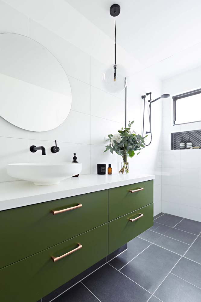 Já nesse aqui, a decoração optou pela composição inversa: um verde musgo mais vibrante nos armários, piso cinza e branco no restante do banheiro.