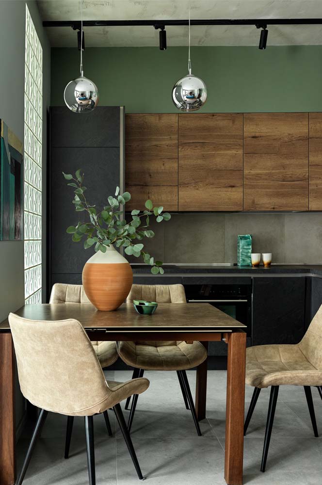 Pintando só a parte da parede acima dos armários, o verde musgo traz um toque a mais de cor para essa cozinha que une madeira, preto, cinza e bege.