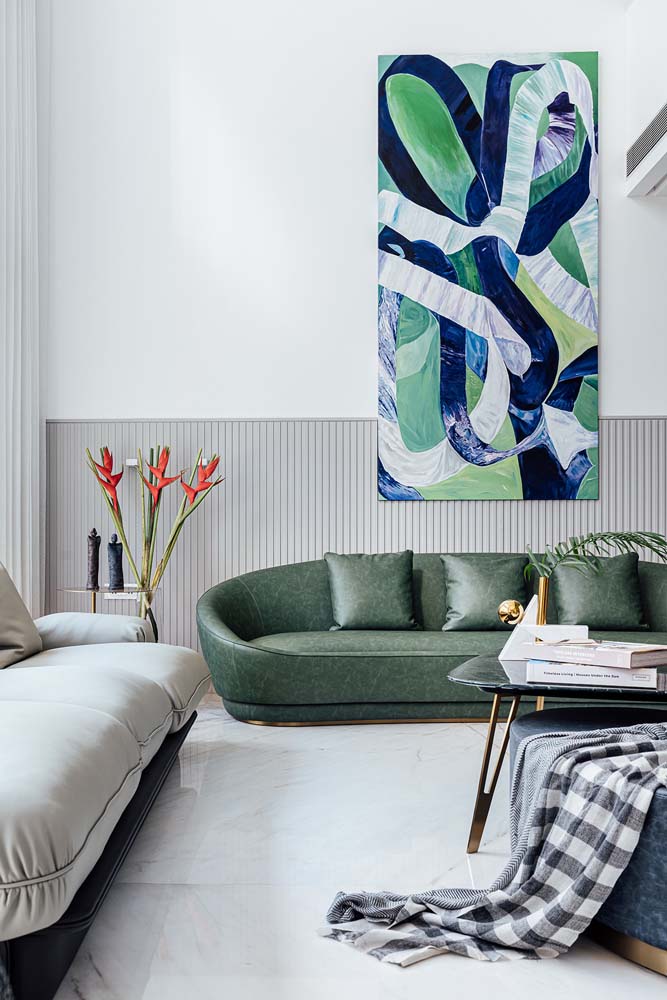 Nessa sala moderna ampla e clara, todas as atenções ficam voltadas para o sofá verde musgo e o quadro que remete à natureza pendurado logo acima. 