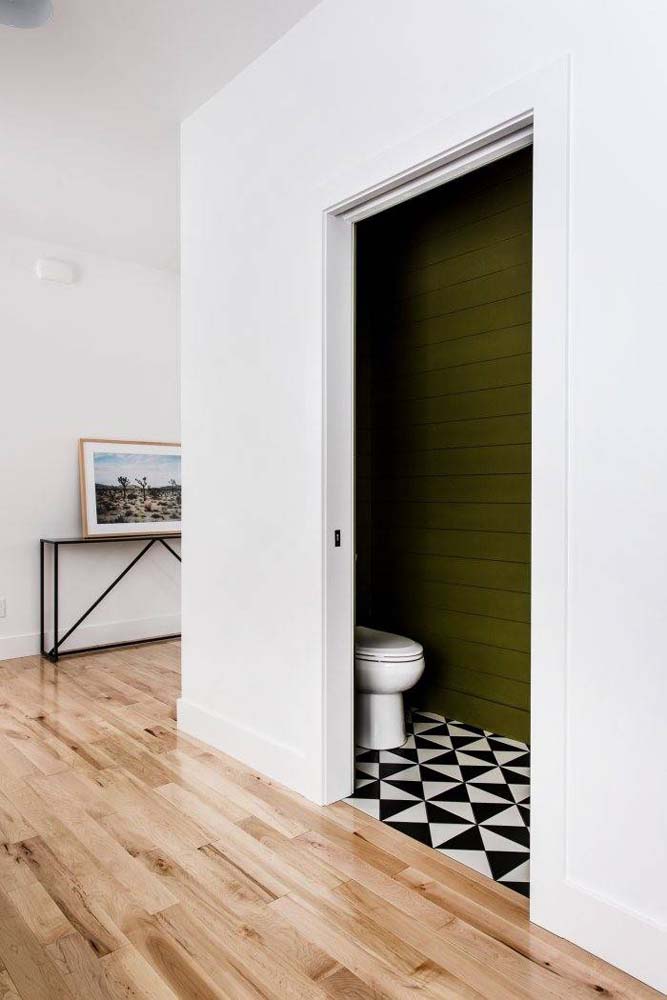 Verde musgo intenso nos painéis horizontais que cobrem as paredes desse pequeno lavabo. 
