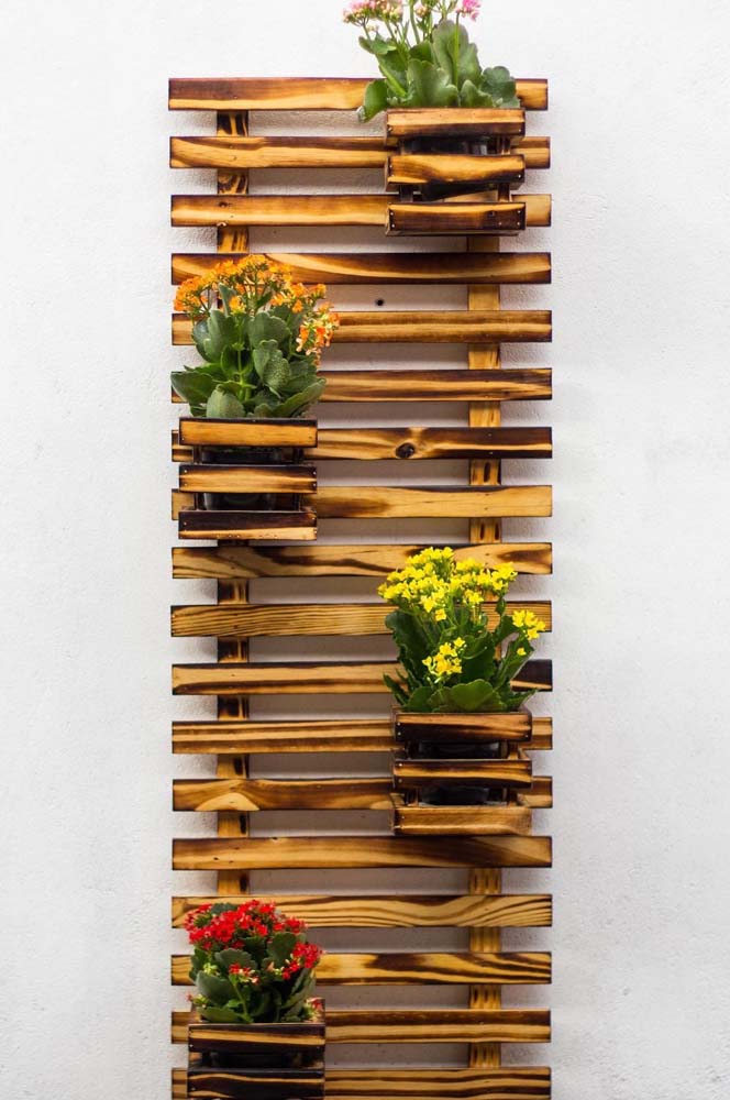 Um modelo simples de floreira de pallet vertical, com vasos de madeira intercalados, garantindo bastante espaço para as plantas crescerem.