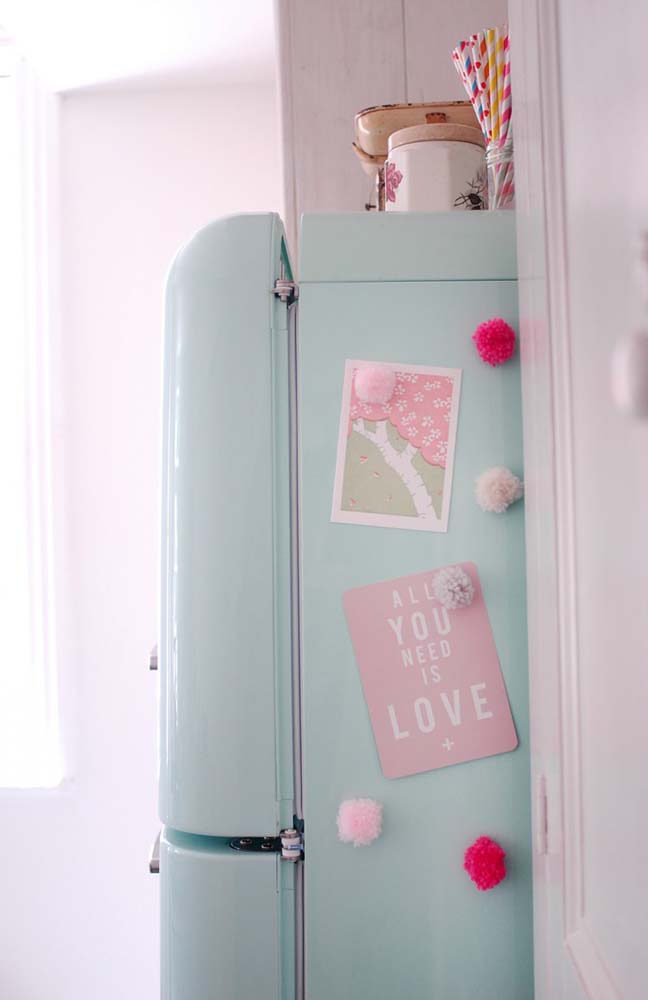 Um toque a mais de fofura nessa geladeira decorada com cartões ilustrados fixados com ímãs-pompons em tons de rosa.