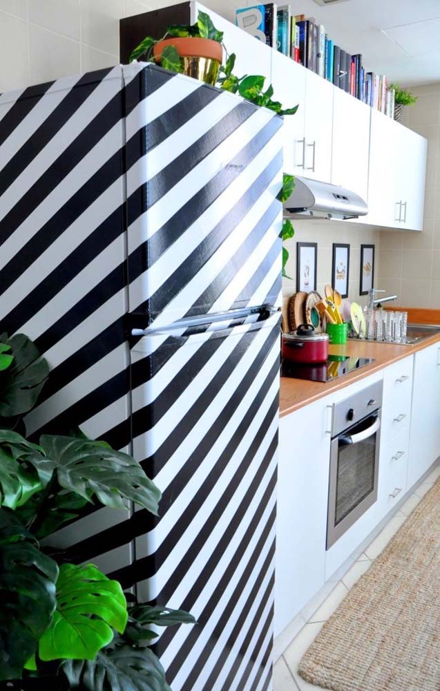 Use fitas adesivas para delimitar as linhas e pintar linhas diagonais retíssimas com tinta preta e fazer uma geladeira decorada listrada como essa!