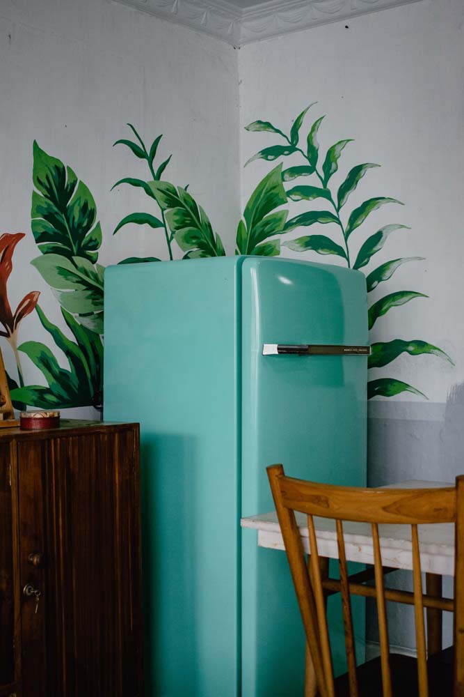 Quer fazer uma geladeira decorada mas sem transformar o eletrodoméstico? Então experimente aplicar papel de parede ou fazer uma pintura interessante nas paredes ao redor!