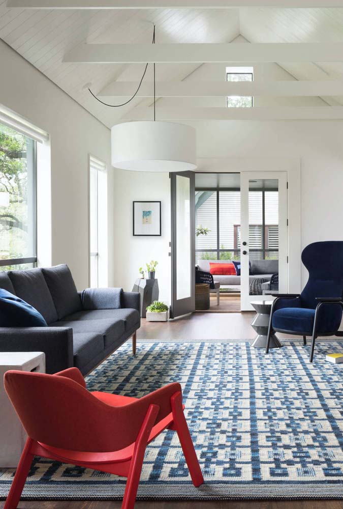O vermelho da cadeira quebra o clima frio da paleta cinza e azul da sala de estar.