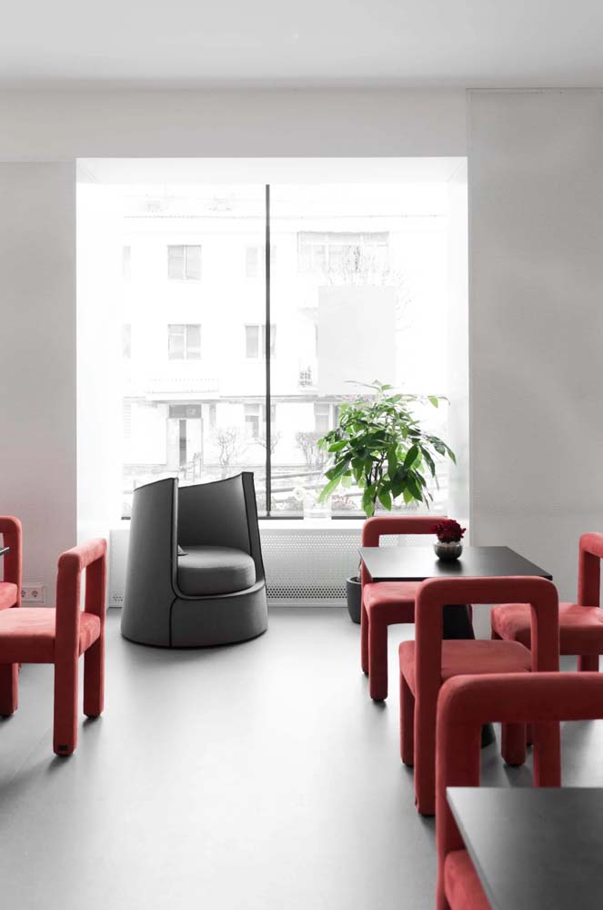 Ambiente moderno, simples e sofisticado com mesa quadrada preta e cadeiras vermelhas de tecido.