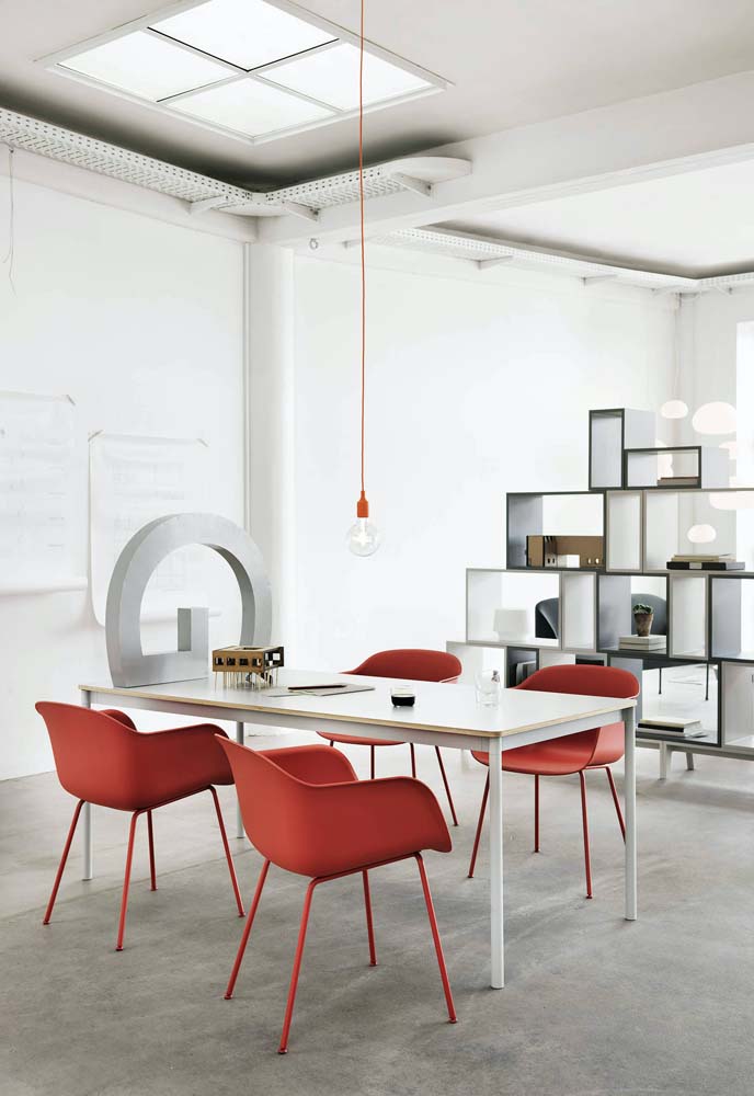 Na sala de reuniões minimalista, as cadeiras vermelhas chamam toda a atenção.