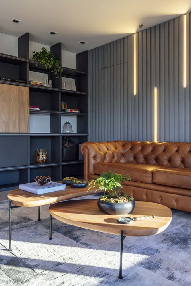 Clássico que é clássico nunca sai de moda: é o caso desse sofá chesterfield de couro caramelo nesse escritório moderno.