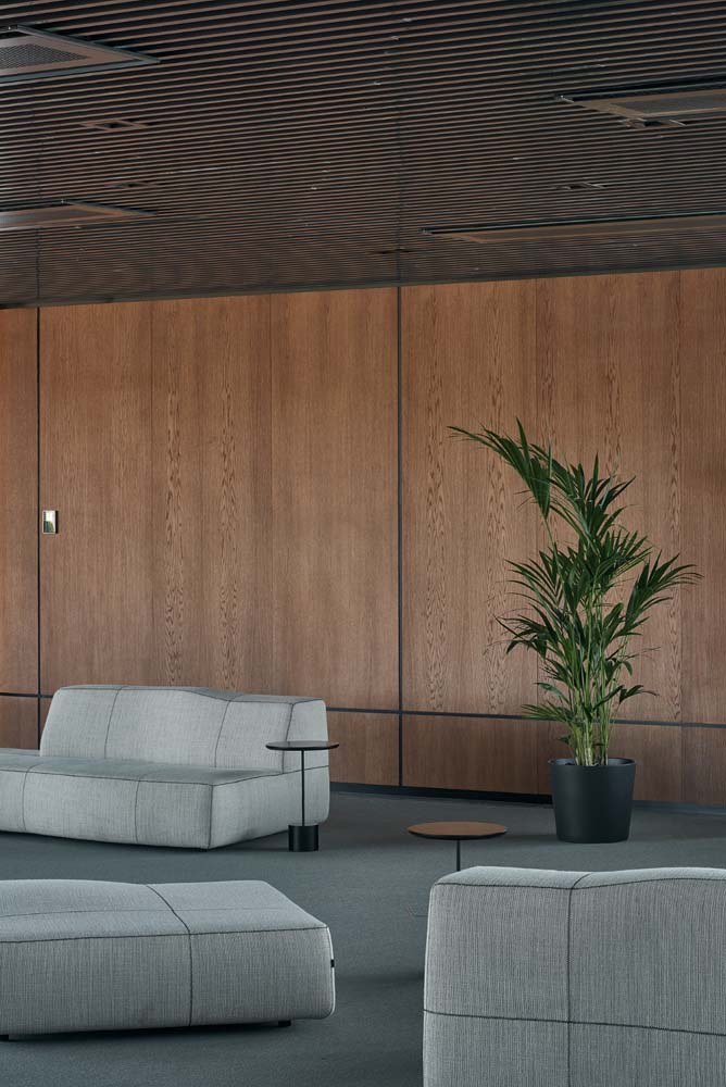 Espaço de espera sóbrio, elegante e bem amplo com vários sofás para escritório pequenos dispostos de diferentes formas.