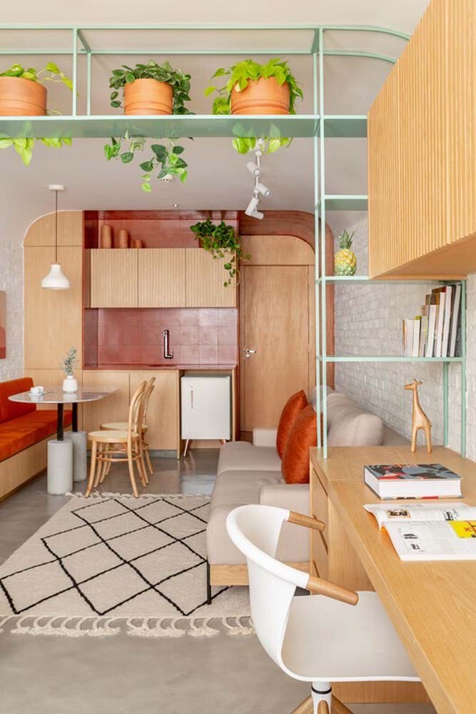 No escritório integrado à sala e cozinha de casa, o sofá é compartilhado entre os ambientes. 