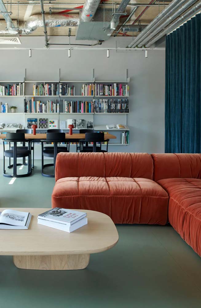 O sofá modular laranja quebra o frio do azul que predomina neste escritório moderno. 